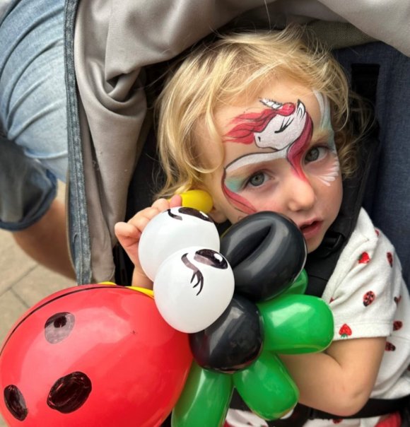 child with face paints and balloon